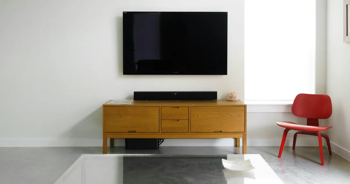 A wall-mounted TV above a wood media console